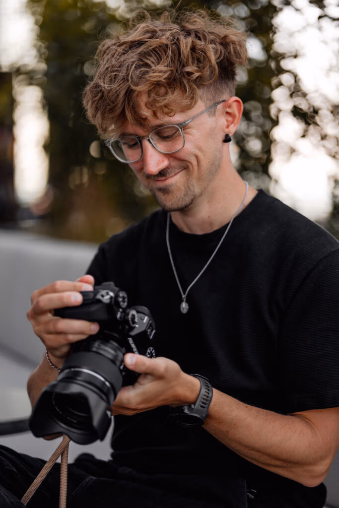 Matthias hält seine Fujifilm-Kamera und lächelt bei der Arbeit.